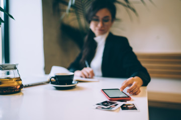 Serious businesswoman using smartphone while working at coffee shop