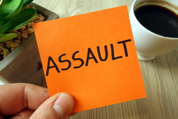 Assault word handwritten on sticky note