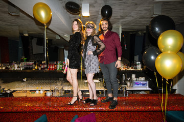 Two pretty girls and elegant guy standing on counter in luxurious restaurant