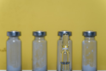 Glass medical ampoule vial for injection. Medicine is liquid sodium chloride with of aqueous solution in ampulla. Close up. Bottles ampule multicolor on background color and water. Human plasma.