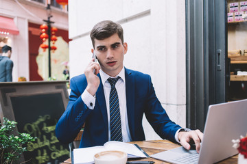 Puzzled businessman looking aside while having phone conversation