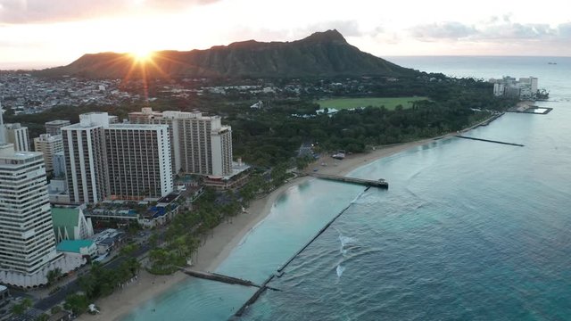 sunrise over Diamond Head flying backward revealing Waikiki Beach