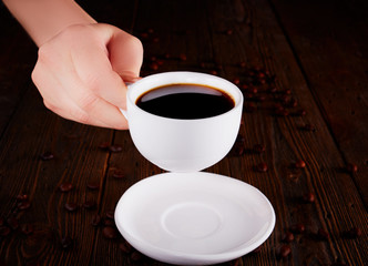 Woman Hand Raising A Cup Of Coffee From Wooden Table