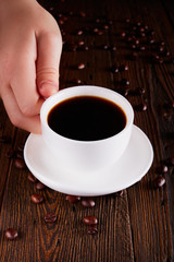 Woman Hand Raising A Cup Of Coffee From Wooden Table