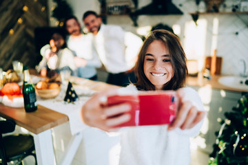 Cheerful group of friends capturing selfie together by mobile while celebrating Christmas at home