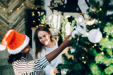 Happy diverse women decorating Christmas tree