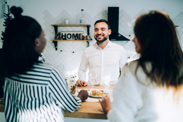 Smiling man talking with friends on kitchen table