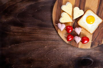 Cooking, sandwiches, heart-shaped snacks, top view. Heart-shaped sausages and sandwiches with cherry tomatoes with croutons on a wooden table. Valentine's Day