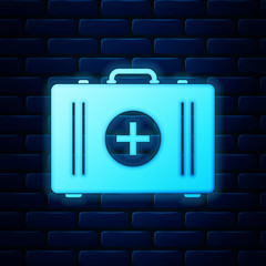 Glowing neon First aid kit icon isolated on brick wall background. Medical box with cross. Medical equipment for emergency. Healthcare concept. Vector Illustration