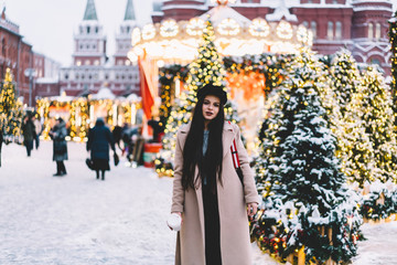 Young woman standing among Christmas trees on street