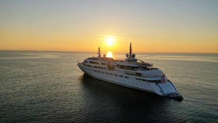 Aerial drone photo of luxury yacht docked in Aegean deep blue sea at sunset with beautiful golden colours, Greece