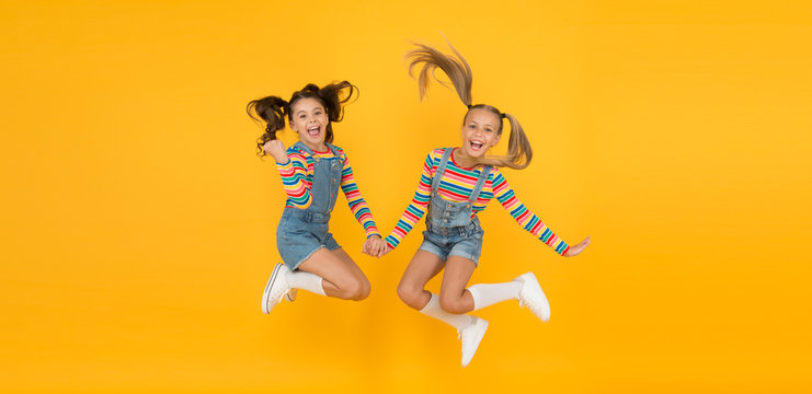 party fun time. little girls jump yellow wall. sense of freedom. finally summer vacation. free and energetic beauty. happy childhood. real friendship. best friends forever. small sisters have fun