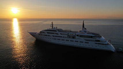 Fototapeta na wymiar Aerial drone photo of luxury yacht docked in Aegean deep blue sea at sunset with beautiful golden colours, Greece
