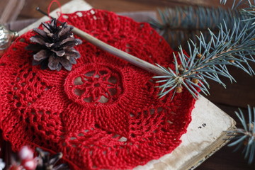 Crocheted doily in red. The concept of needlework, winter pastime, comfort, home warmth.