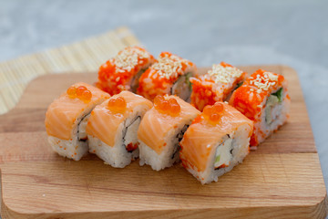 Japanese cuisine. Sushi roll with salmon, leeks, tuna, avocado, king prawn, Philadelphia cream cheese, caviar with tobiko. Sushi menu. The view from the top. rolls on a wooden Board.