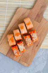 Japanese cuisine. Sushi roll with salmon, leeks, tuna, avocado, king prawn, Philadelphia cream cheese, caviar with tobiko. Sushi menu. The view from the top. rolls on a wooden Board.