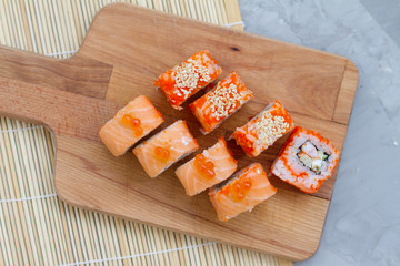 Japanese cuisine. Sushi roll with salmon, leeks, tuna, avocado, king prawn, Philadelphia cream cheese, caviar with tobiko. Sushi menu. The view from the top. rolls on a wooden Board.