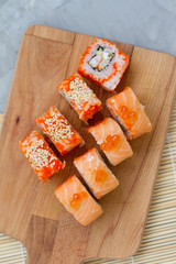 Japanese cuisine. Sushi roll with salmon, leeks, tuna, avocado, king prawn, Philadelphia cream cheese, caviar with tobiko. Sushi menu. The view from the top. rolls on a wooden Board.