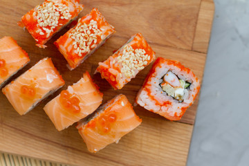 Japanese cuisine. Sushi roll with salmon, leeks, tuna, avocado, king prawn, Philadelphia cream cheese, caviar with tobiko. Sushi menu. The view from the top. rolls on a wooden Board.