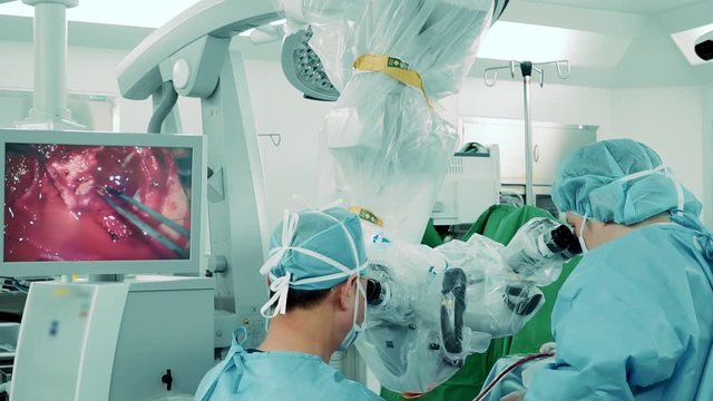 Human skull surgery via electronic microscope image on monitor