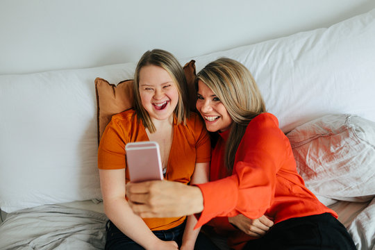 Sisters on bed taking selfie