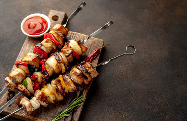 Meat skewers with grilled vegetables on a cutting board on a stone background with copy space for...