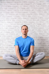 Fototapeta premium Peaceful attractive man practising yoga, meditating at home. Joyful man undergoing morning exercises. Vertical