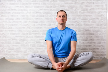Fototapeta premium Middl aged man prefers healthy lifestyle. Joyful man undergoing morning exercises. Attractve man performing yoga while sitting at home