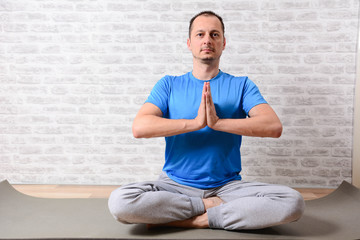 Calm Mddle aged man wearing athletic wear sitting on  exercising yoga. peaceful  male practice yoga at home relieve stress or renew energy, man do physical exercises following healthy lifestyle