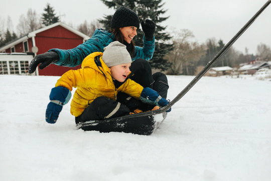 Mother with son on sleigh snow shovel
