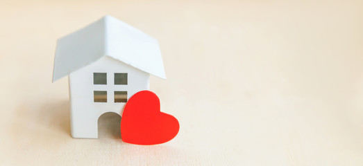 Miniature toy model house with red heart on wooden backdrop. Eco Village abstract environmental background. Real estate mortgage property insurance sweet dream home ecology concept