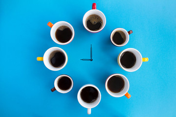 Coffee time. Composition with black coffee in bright cups and clock hands in the center of the blue  background. Top view. Copy space.