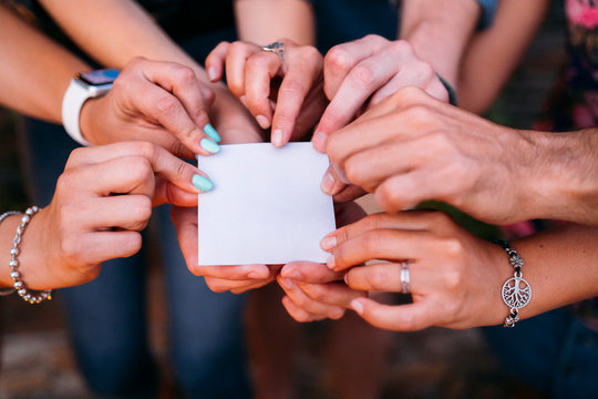 Close-up of friends holding a blank card