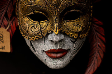 wooden mask on black background colour red and gold