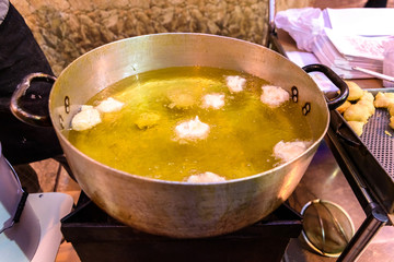 typical Italian fried fritters in a pot with oil.