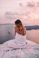 Young woman wrapped in sheets with blonde hair in santorini greece