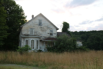 Obraz premium Old abandoned historic farmhouse with broken windows and peeling paint