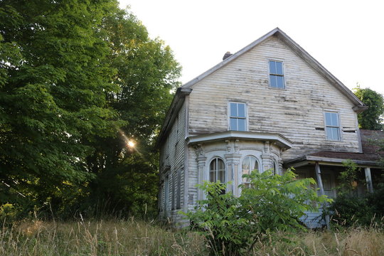 Old abandoned historic farmhouse with broken windows and peeling paint