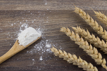 Whole flour with wheat on wooden table, top view