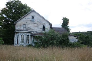 Fototapeta na wymiar Old abandoned historic farmhouse with broken windows and peeling paint