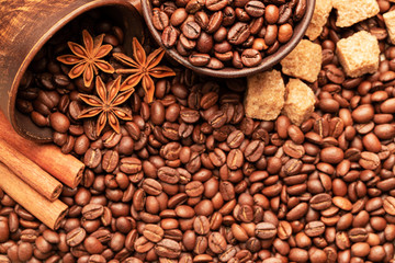 A clay bowl filled with coffee beans and star anise and cinnamon  against the background of cane sugar and coffee beans.