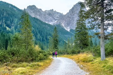 Fototapeta na wymiar Hiking trip, Dolomites landscape. Pair of tourists is walking along a wide trail in the Dolomites. The Tofane Group in the Dolomites, Italy, Europe.