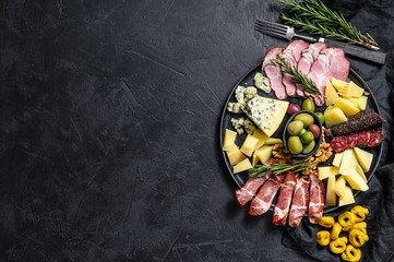 Typical italian antipasto with prosciutto, ham, cheese and olives. Black background. Top view....