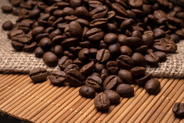 Beautiful large coffee beans are scattered on the table. Beautiful scenery, burlap.