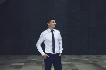 Smiling adult male worker in formal outfit standing in workplace