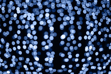Trendy color of the year 2020. Photo of blue bokeh lights on black background. Perfect for overlay.
