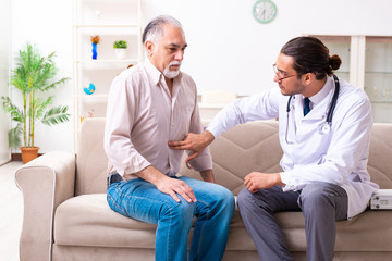 Fototapeta premium Young male doctor visiting old patient at home
