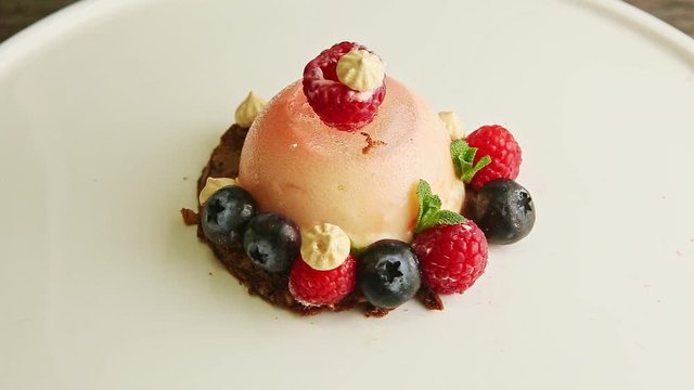 slow zoom in at icing dessert finely decorated with berries rotates on plate