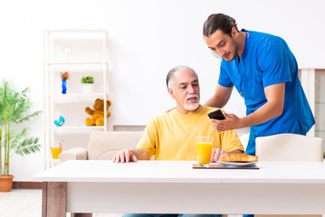 Young male doctor visiting old patient at home