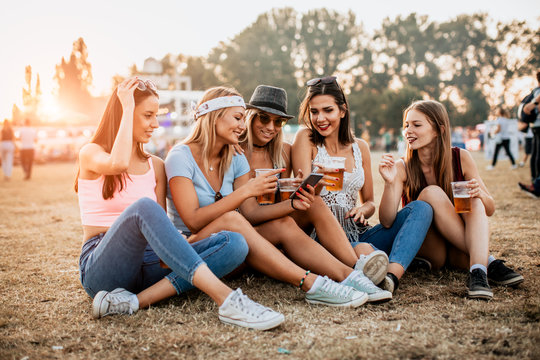 Female friends having fun and using phones at music festival